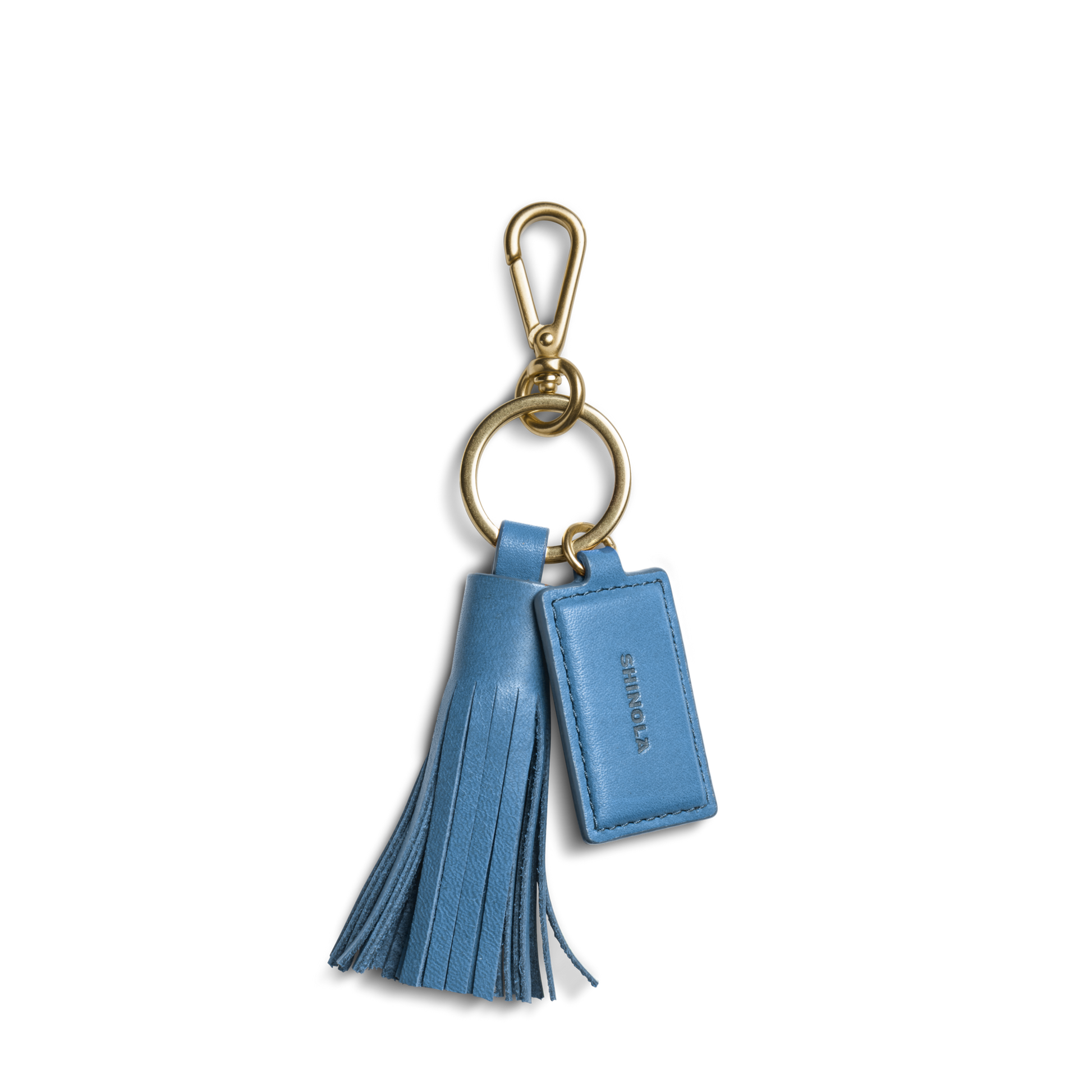 The Shinola Leather Tassel Keychain - River is a blue leather keychain with a gold clasp, tassel, and a small tag embossed with SHINOLA—stylish and perfect for your keys.