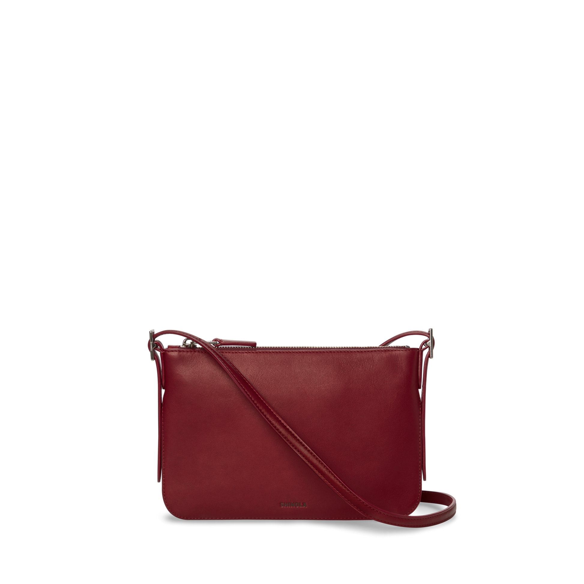 The Shinola Small Bixby Crossbody - Ruby is a sleek, rectangular natural leather bag in dark red with a long strap and top zipper, perfect for daily use, shown against a plain white background.