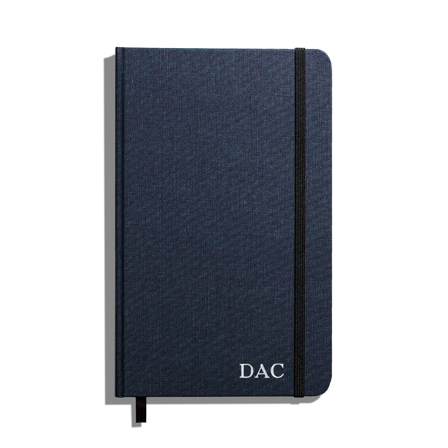 The Shinola Medium Hard Ruled Journal in navy features a durable linen cover, smyth-sewn binding, elastic band closure, and “DAC” initials printed in white at the bottom right corner.