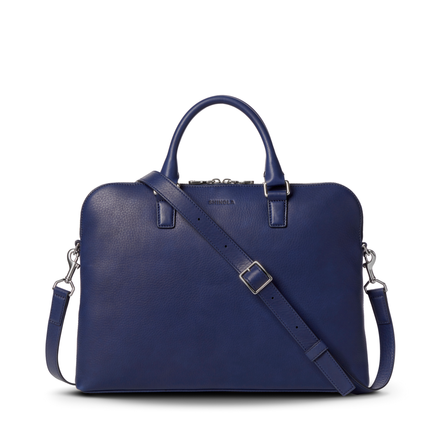 The Shinola Portfolio Briefcase - Lake is a stylish, dark blue slim laptop bag made from European grain leather, featuring a detachable shoulder strap, top handles, and silver hardware, set against a plain white background.