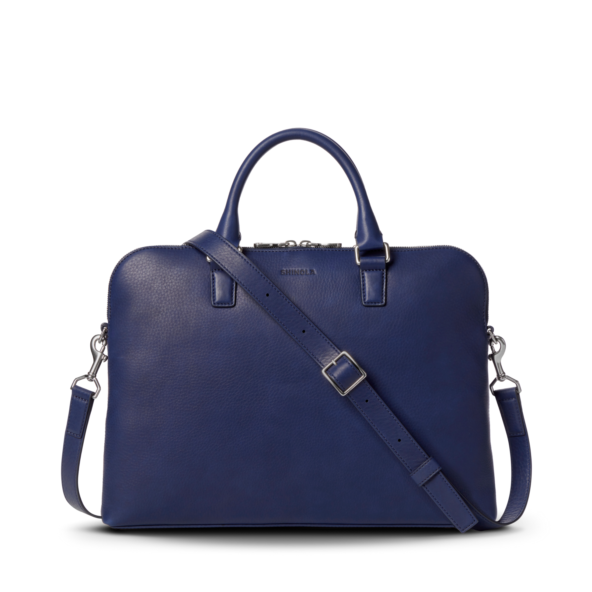 The Shinola Portfolio Briefcase - Lake is a stylish, dark blue slim laptop bag made from European grain leather, featuring a detachable shoulder strap, top handles, and silver hardware, set against a plain white background.