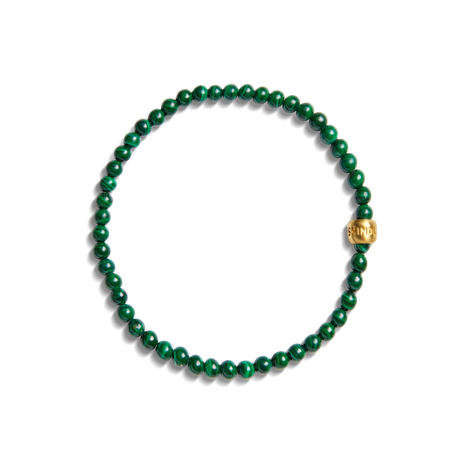The Shinola 4mm Beaded Bracelet Malachite features green round malachite beads and a single larger engraved brass accent bead, arranged in a circle on a white background.