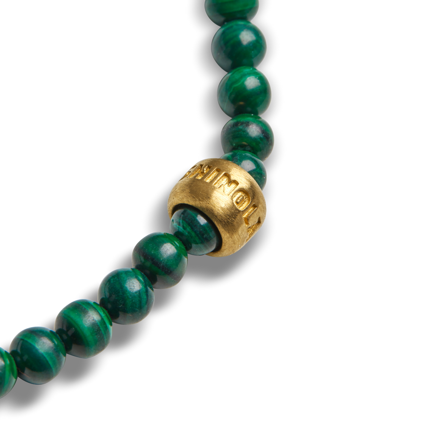 A close-up of the Shinola 4mm Beaded Bracelet Malachite, showcasing round malachite beads and a single large brass accent bead with engraved lettering.