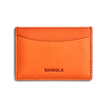 A tangerine Leather 3 Pocket Card Case by Shinola featuring visible stitching, three pockets, and the Shinola name embossed at the bottom center.