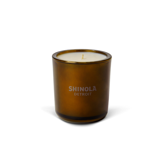 The Shinola Smoke 8oz Scented Candle features a brown glass vessel, white coconut soy wax, and a single wick. With "SHINOLA DETROIT" on the front, this fall candle offers a woody aroma in sleek packaging.