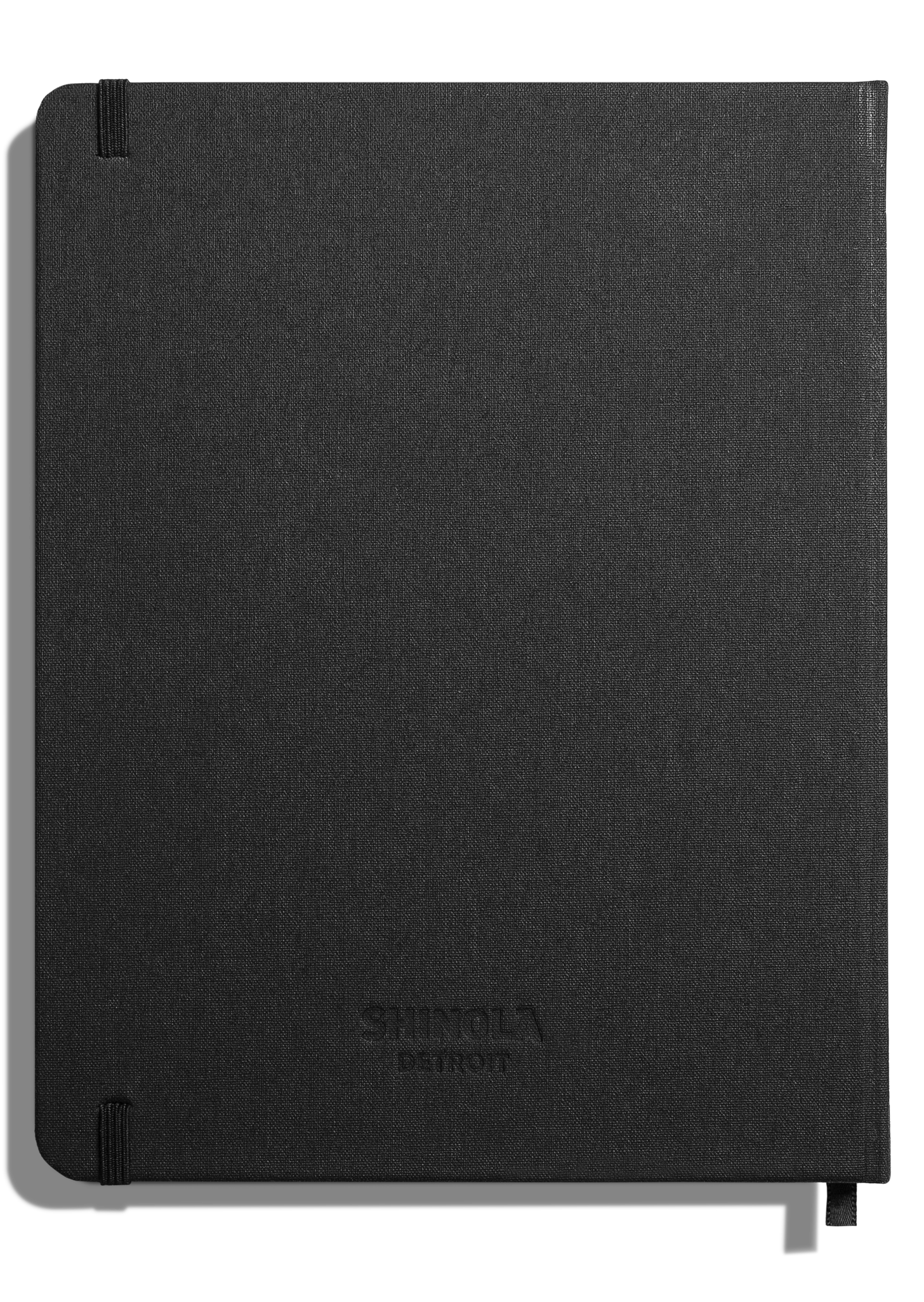 The Shinola Large Hard Ruled Journal in black features a fabric cover, rounded corners, acid-free pages, elastic closures on the top and bottom left, and a subtle Shinola logo embossed on the front.