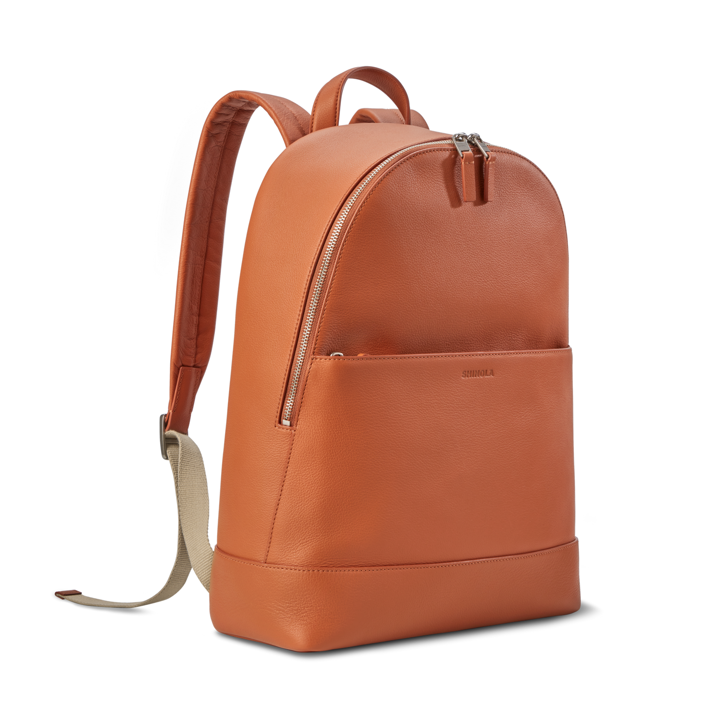 The Shinola Canfield Backpack in Rust features orange leather, a front zip pocket, beige adjustable straps, and a top handle—ideal as a laptop backpack for work or travel—shown on a plain white background.