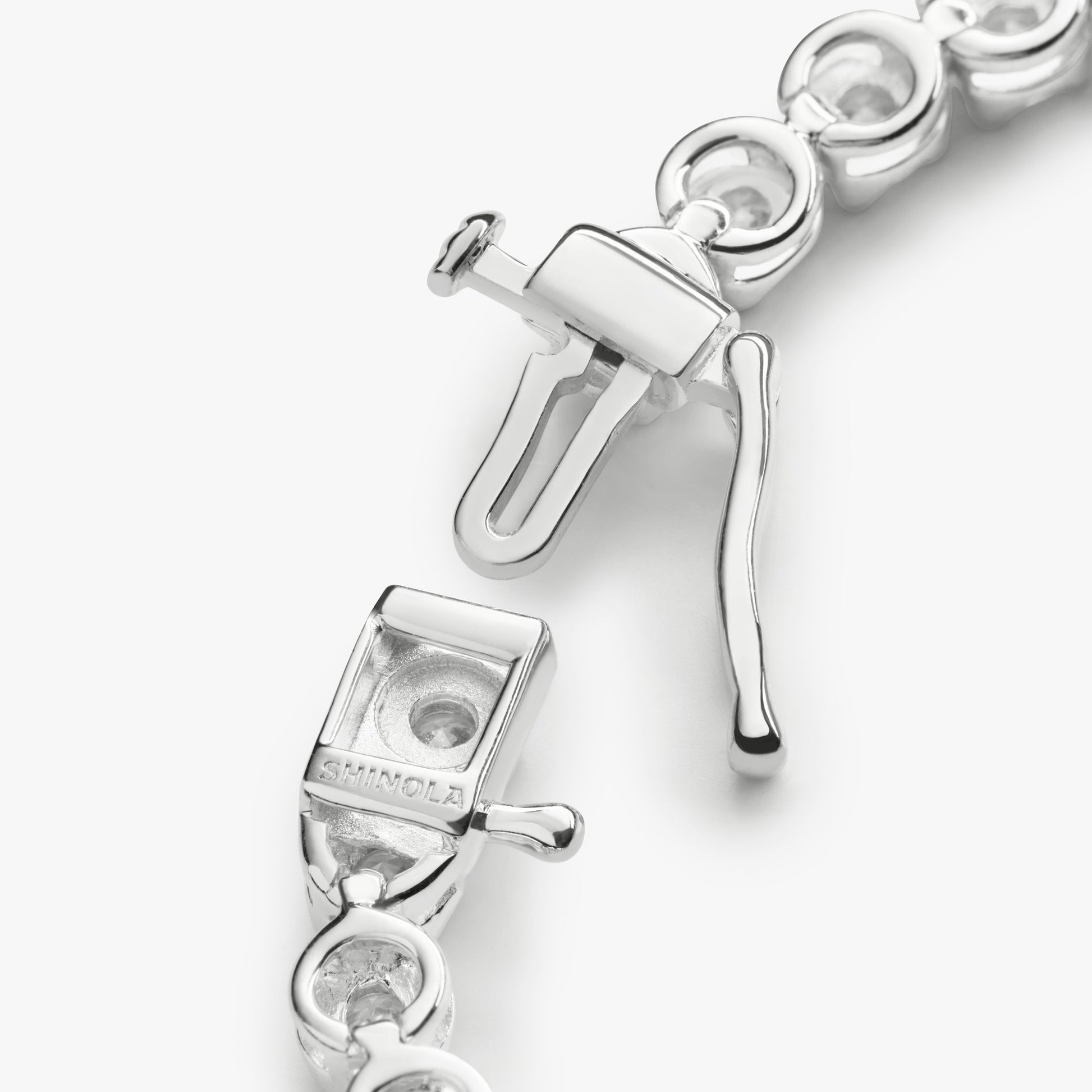 Close-up of the Shinola 3 Carat 7" Diamond Tennis Bracelet in white gold, featuring a box clasp with safety latch, open clasp mechanism, and circular links. "SILMCLA" is engraved on part of the clasp.