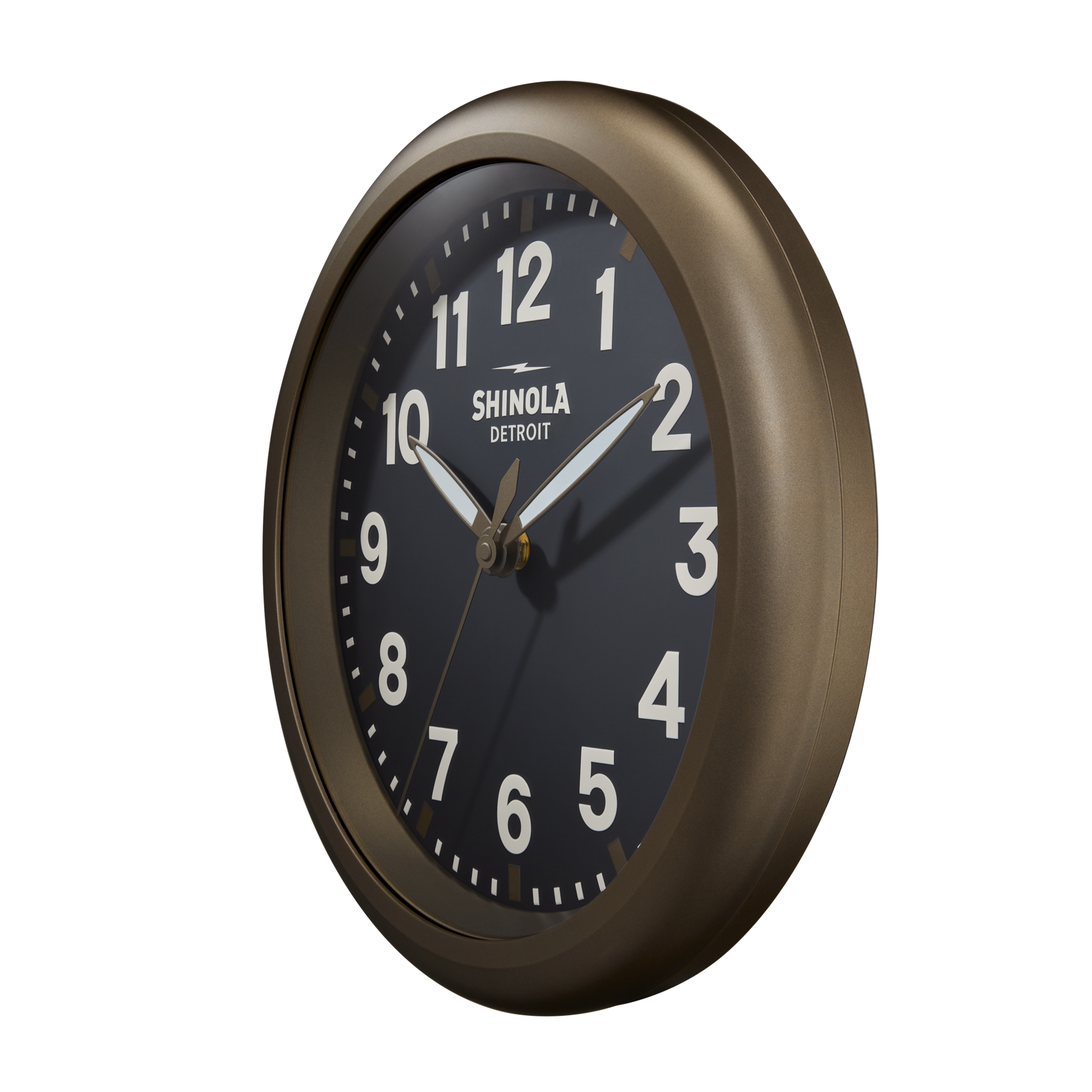 The 14" Runwell Clock by Shinola features a black face with white numerals and hands in a bronze-toned frame. The Shinola logo is displayed on the dial, with the time set to about 10:09.