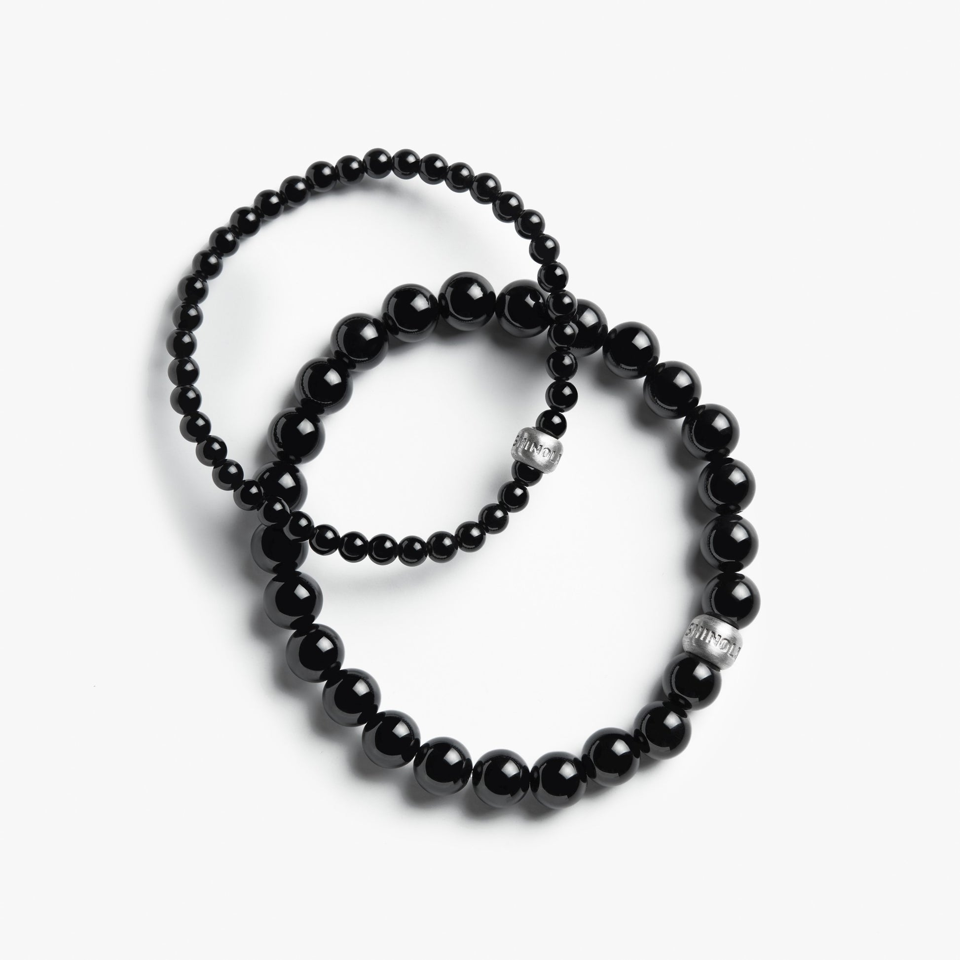 Shinola's 4mm Beaded Onyx Bracelets—two sizes, each with sterling silver accents—are styled in classic onyx fashion and elegantly arranged on a white background.