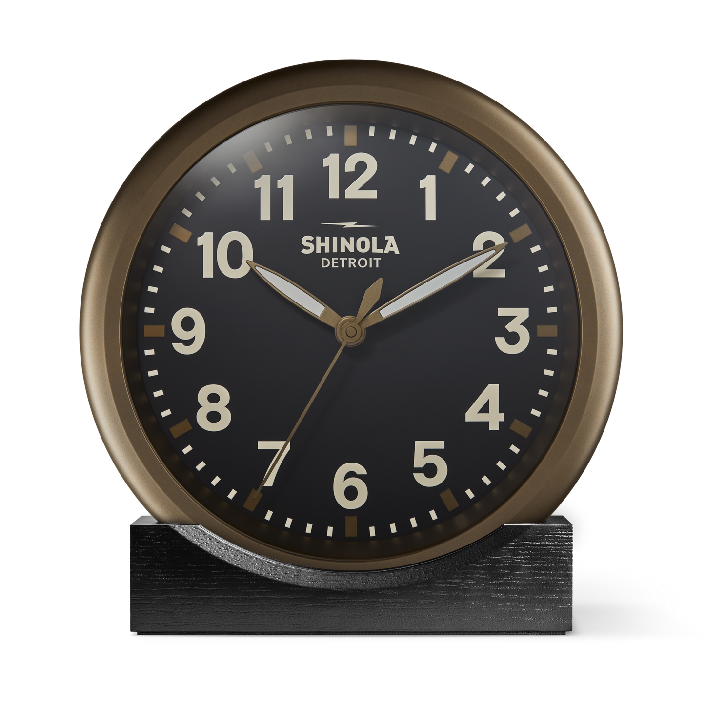 The 14" Runwell Clock by Shinola features a round, vintage-inspired design with a black face, white numerals, and gold hands. It sits on a black rectangular base, reads 10:10, and displays 'Shinola Detroit' on the face.