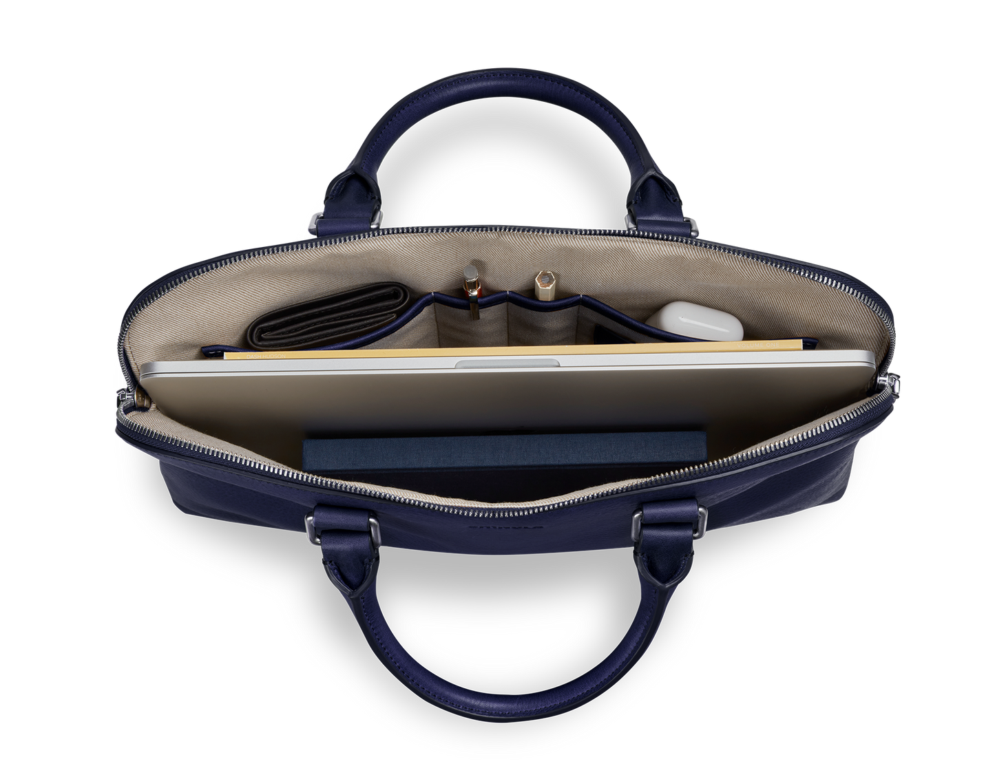 Top view of Shinola’s Portfolio Briefcase - Lake in navy blue European leather, showing a laptop, closed dark wallet, two pens, white case, and dark blue notebook—all neatly organized in separate compartments.