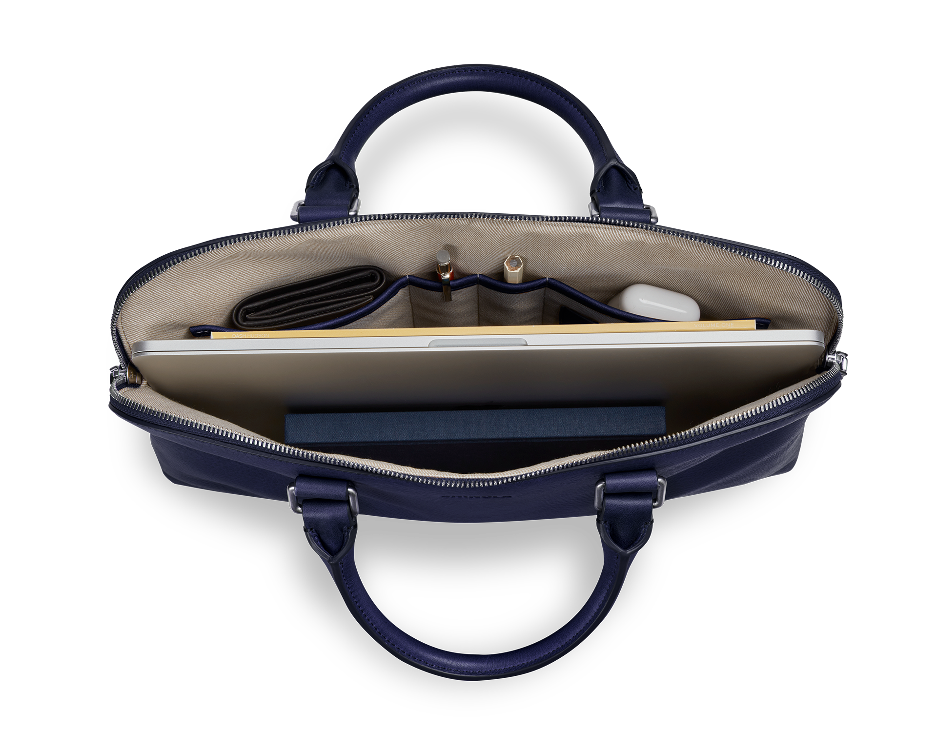 Top view of Shinola’s Portfolio Briefcase - Lake in navy blue European leather, showing a laptop, closed dark wallet, two pens, white case, and dark blue notebook—all neatly organized in separate compartments.