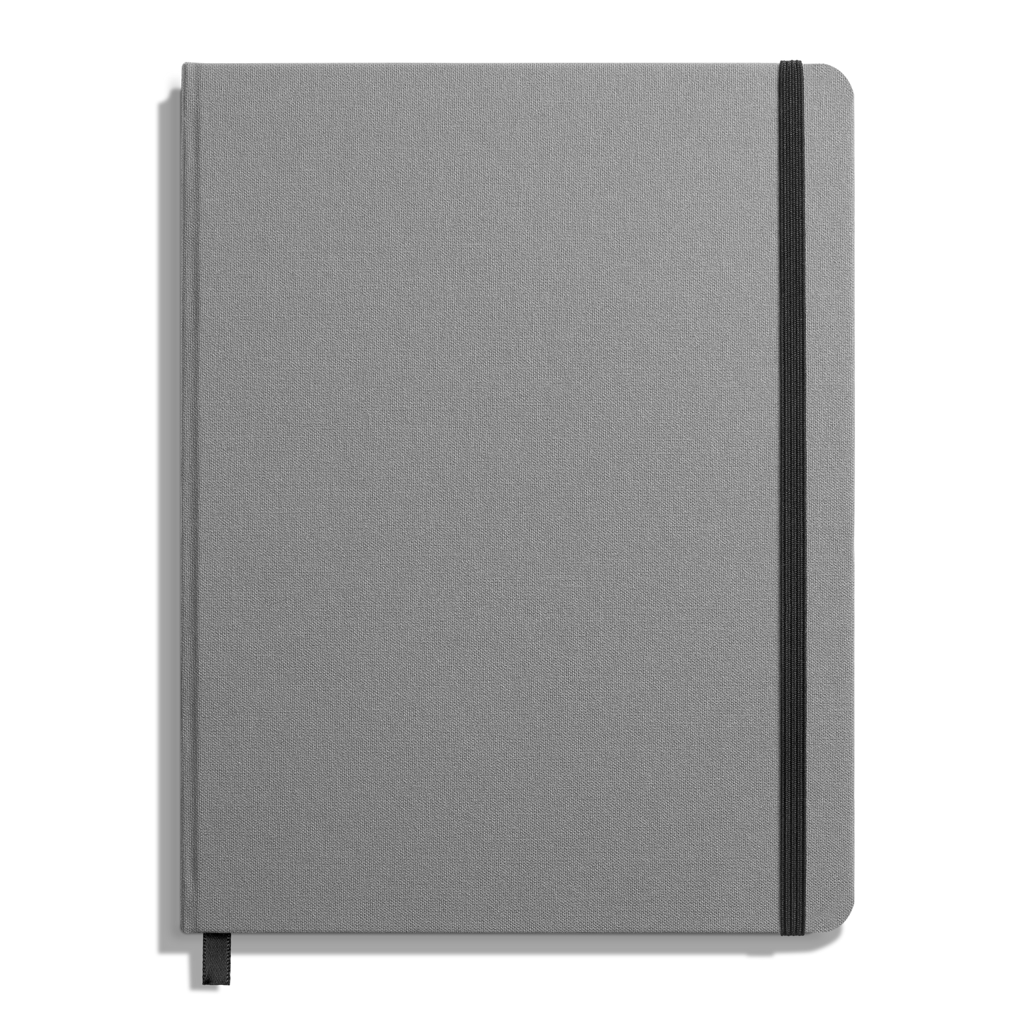 The Shinola Large Hard Grid Journal in Stone features a closed, gray linen cover with a black elastic band on the right edge and a black ribbon bookmark, all set against a white background.