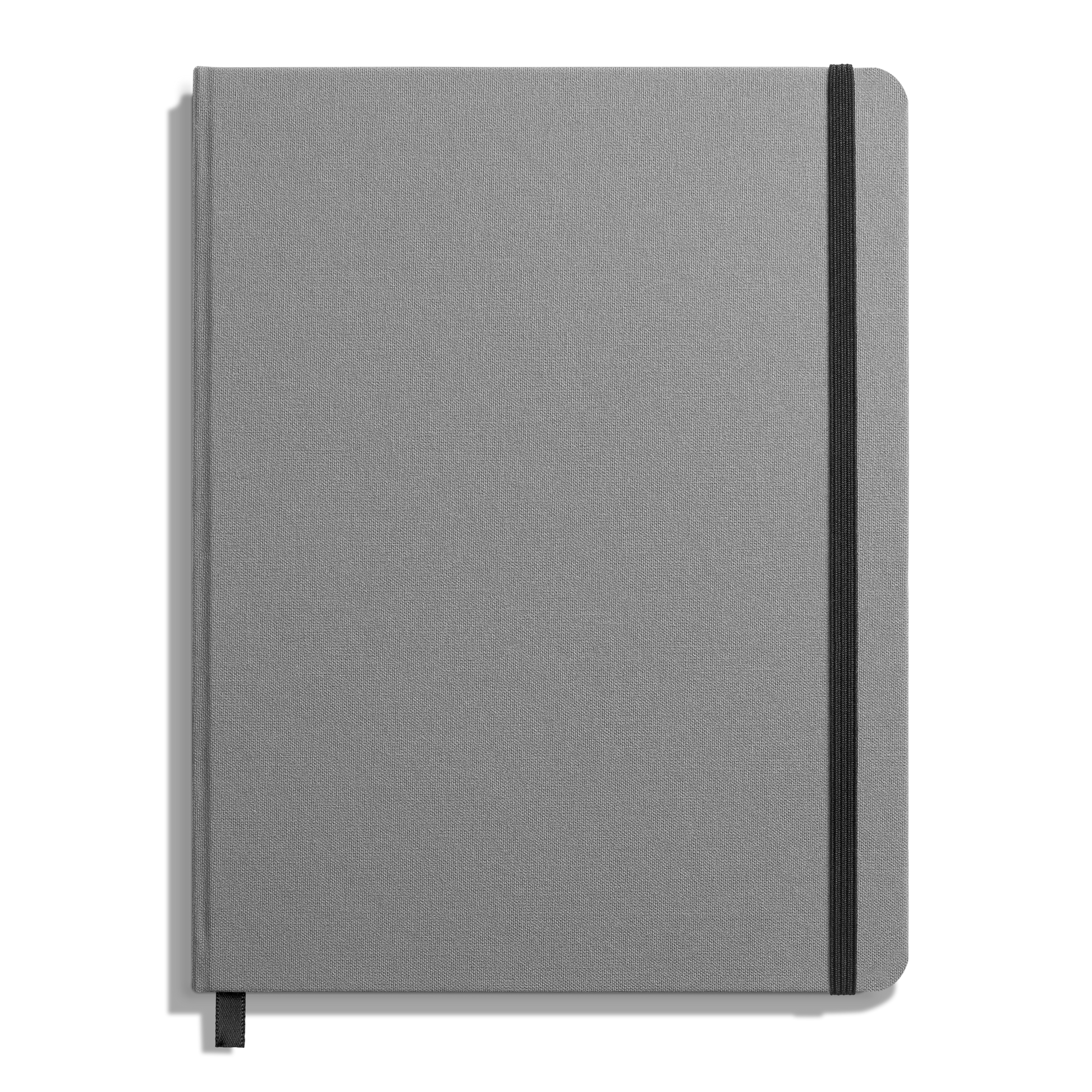The Shinola Large Hard Grid Journal in Stone features a closed, gray linen cover with a black elastic band on the right edge and a black ribbon bookmark, all set against a white background.