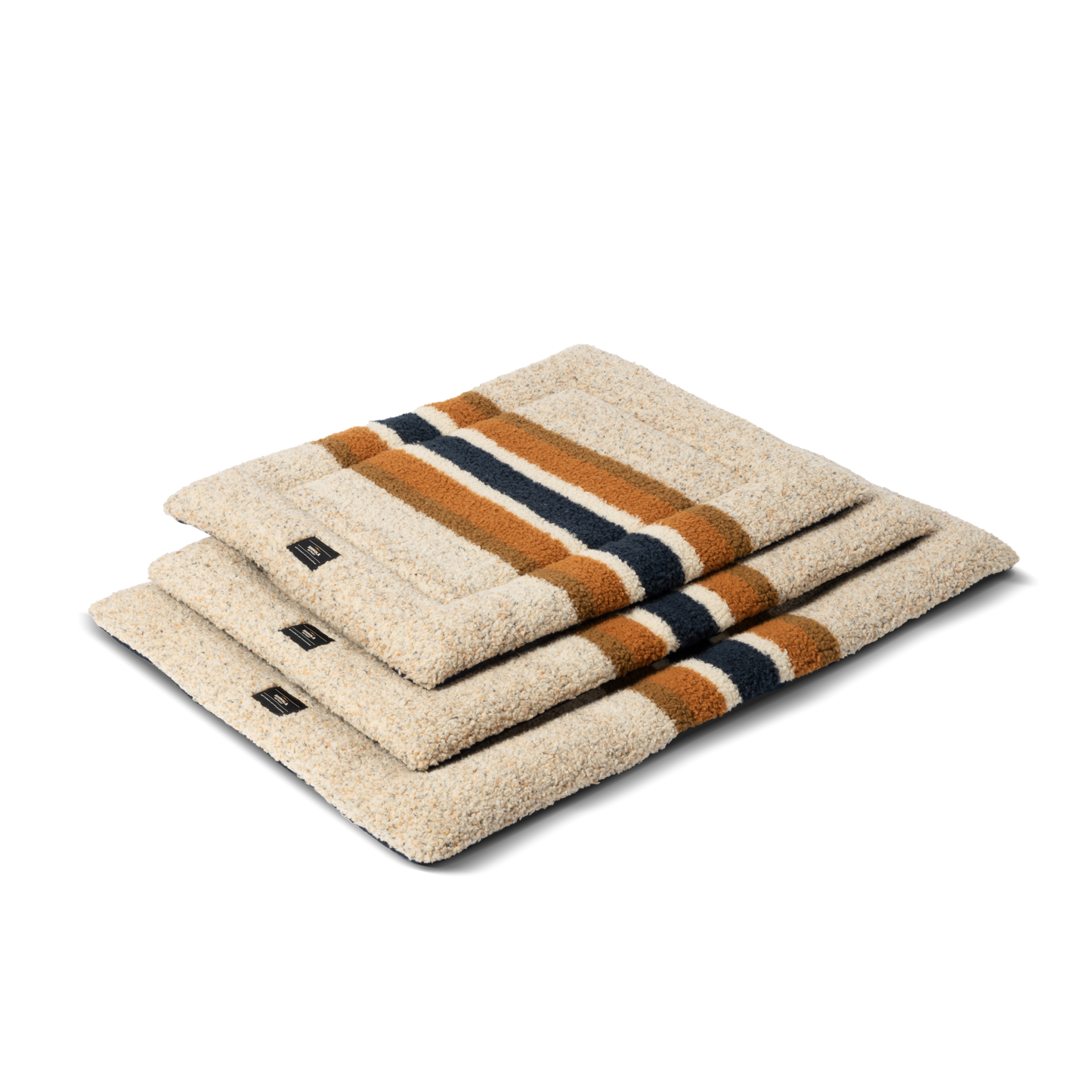 Three folded Crate Comfort Mat - Oat Stripe dog mats by Shinola, featuring beige with navy blue and brown stripes, are stacked atop each other against a plain white background.