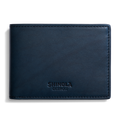 A closed Slim Bifold Wallet in navy leather by Shinola, featuring embossed branding on the lower front, displayed against a plain white background.